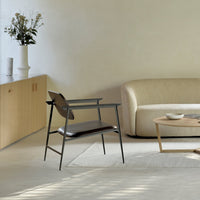 Stylish black chair with a minimalist design, featuring a warm wooden finish and a neutral-toned living space backdrop.