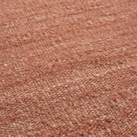 Textured woven rug in warm terracotta hues with subtle, natural patterns. Perfect for cozy interior designs.
