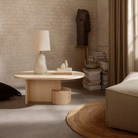 Natural wood coffee table with soft beige lamp, complemented by warm earthy tones and neutral textures.
