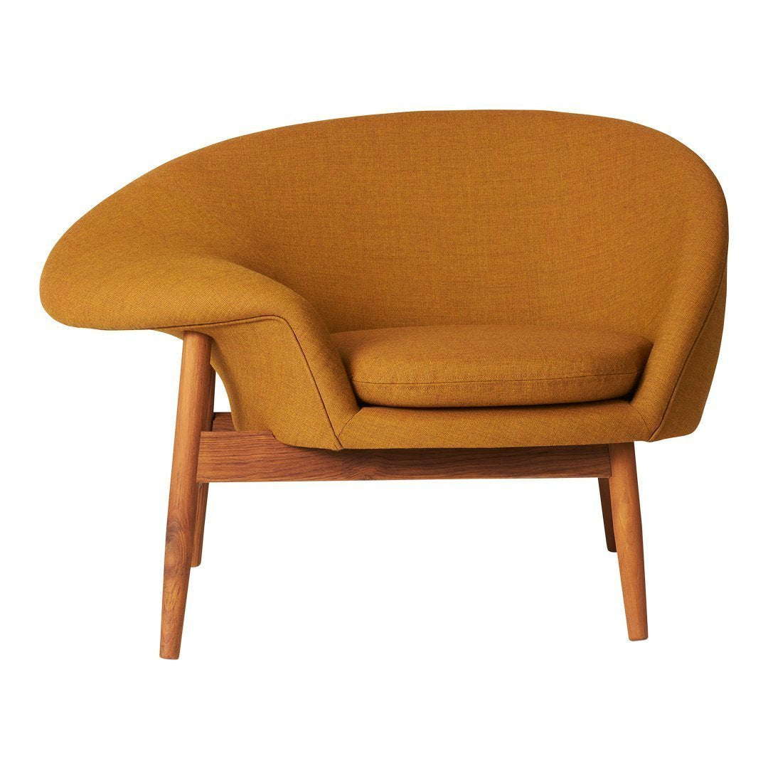 "Mustard yellow upholstered armchair with a smooth, rounded design and wooden legs."