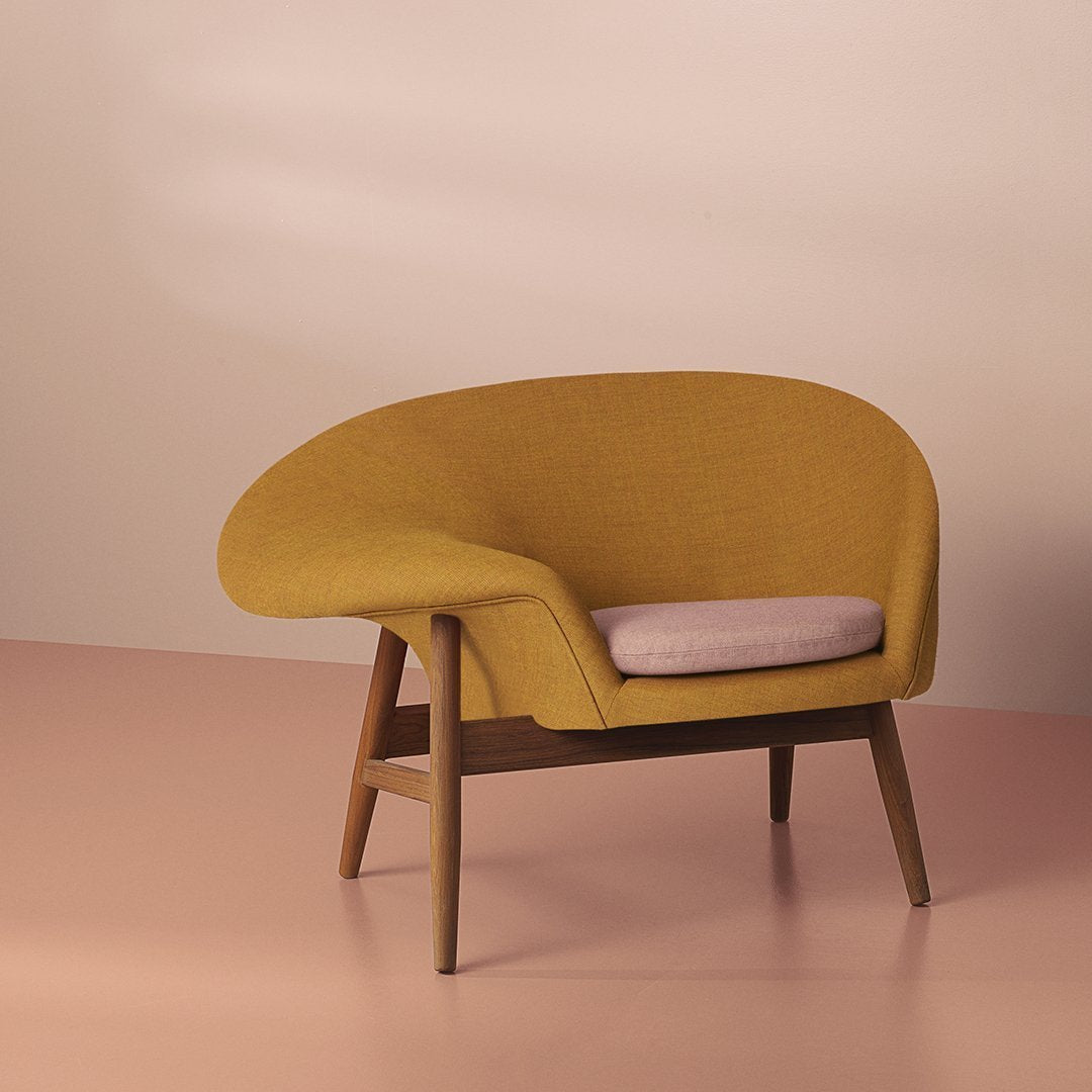 Yellow textured chair with a light pink cushion, set against a soft pastel background. Modern and stylish design.