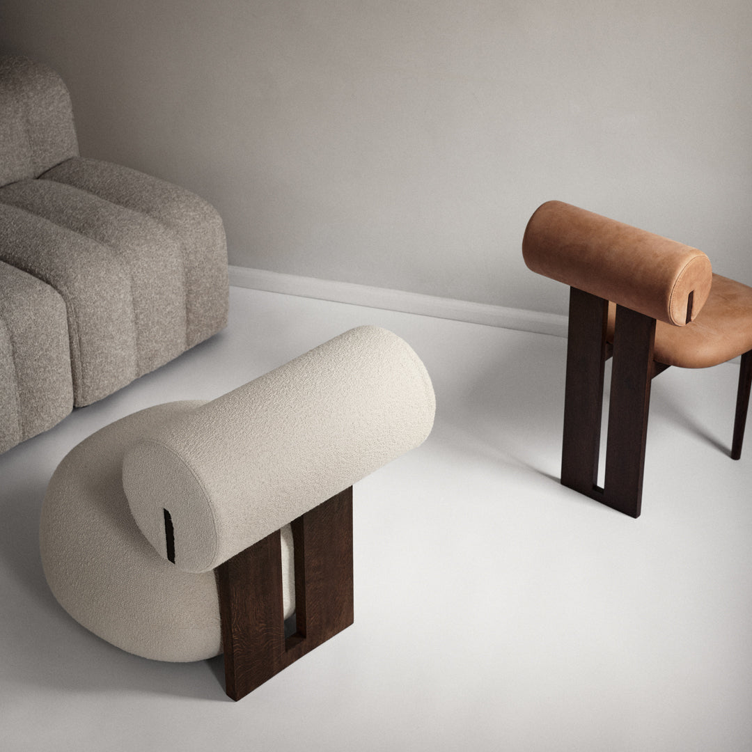  Beige and brown upholstered chairs with cylindrical shapes and dark wooden legs, set on a minimalist background.