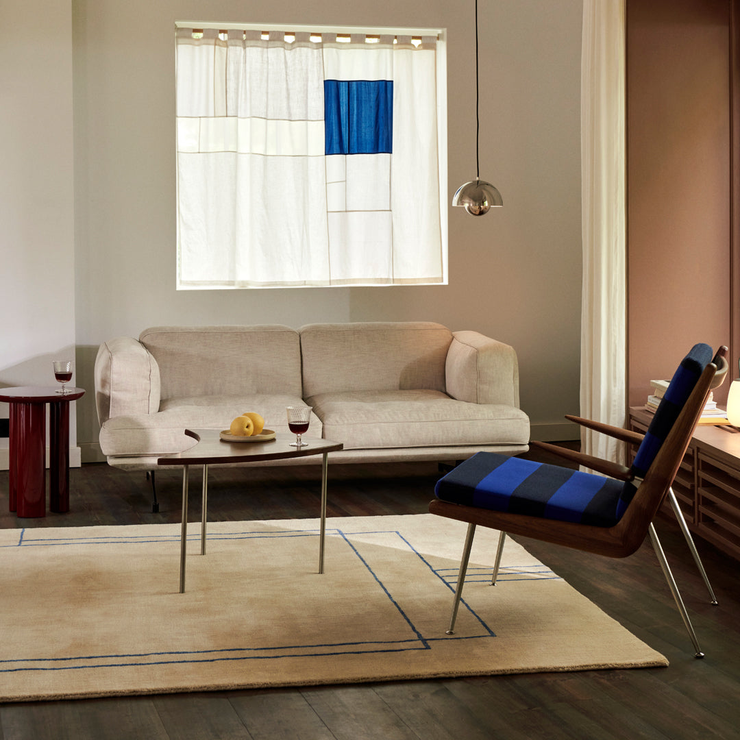 Modern living room featuring a beige sofa, blue striped chair, and a neutral rug with geometric patterns.