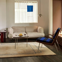 Beige sofa with blue striped chair, neutral rug, and blue accent window, creating a modern, minimalist look.