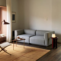 Gray fabric sofa in a minimalist setting with wood accents and a light-colored rug. Clean lines and neutral tones.