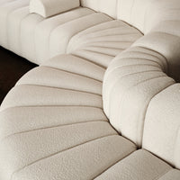 Beige, textured fabric sectional sofa with curved, ribbed patterns and a soft, cozy appearance. Perfect for modern interiors.
