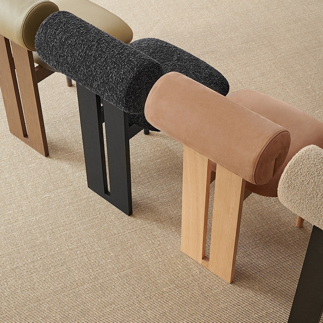 Colorful modern stools featuring black, tan, and muted green upholstery with sleek wooden legs in natural finishes.