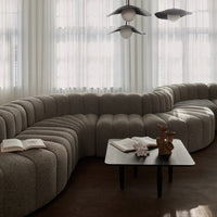 Curved sofa in soft beige fabric, featuring a ribbed texture; modern black table with decorative items.