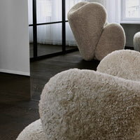 Cream-colored, fluffy heart-shaped chairs on dark wooden floor, creating a modern and cozy aesthetic.