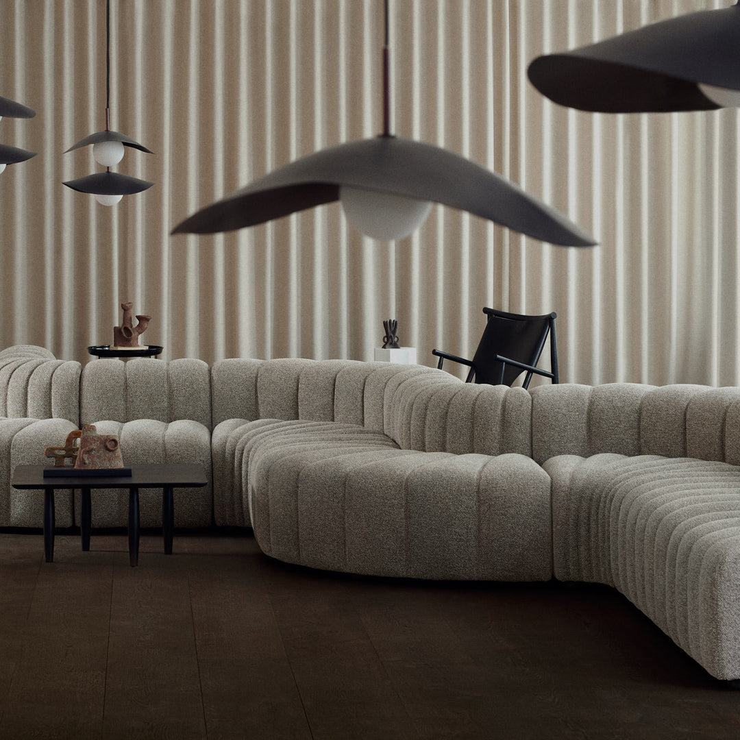 Cozy cream and beige textured sofa with a curved silhouette, complemented by dark accents and pendant lighting.