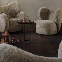 Textured beige upholstery on cozy chairs with organic shapes, accented by a sleek black metal side table.
