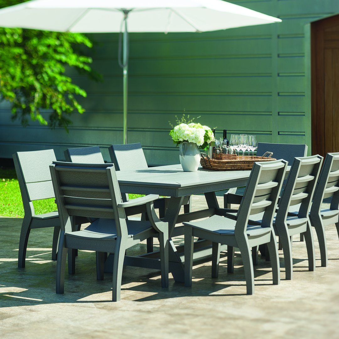Gray outdoor dining set with sleek lines, featuring a rectangular table and matching chairs on a landscaped patio.