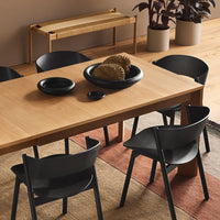 Stylish wooden dining table with black chairs, featuring earthy tones and minimalistic designs. Modern decor elements included.