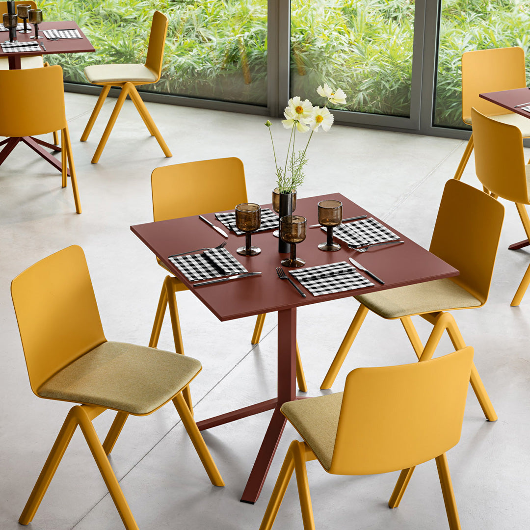 Modern dining set featuring yellow chairs and a burgundy table, accented with black and white patterned tableware.