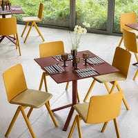 Modern dining set featuring yellow chairs and a burgundy table, accented with black and white patterned tableware.