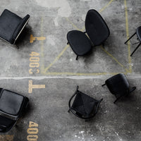 Black chairs in various patterns on a textured concrete floor with yellow markings. Modern minimalist design elements.