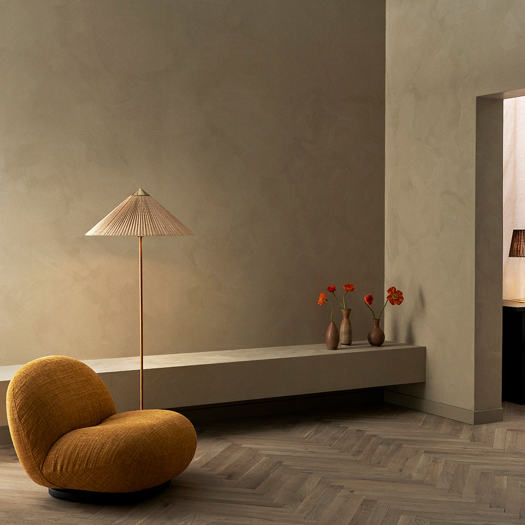Cozy mustard yellow chair against a textured neutral wall, with soft wooden flooring and a minimalist decor.