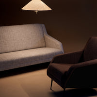 Gray textured sofa and dark brown armchair contrast against a warm, dim background with soft lighting.