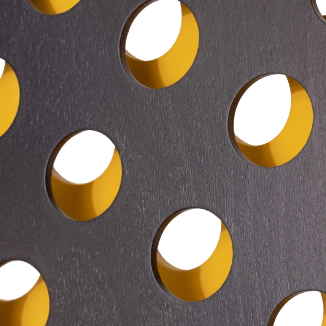 Close-up of a textured gray surface with bold yellow circular cutouts, creating a striking contrast and modern pattern.
