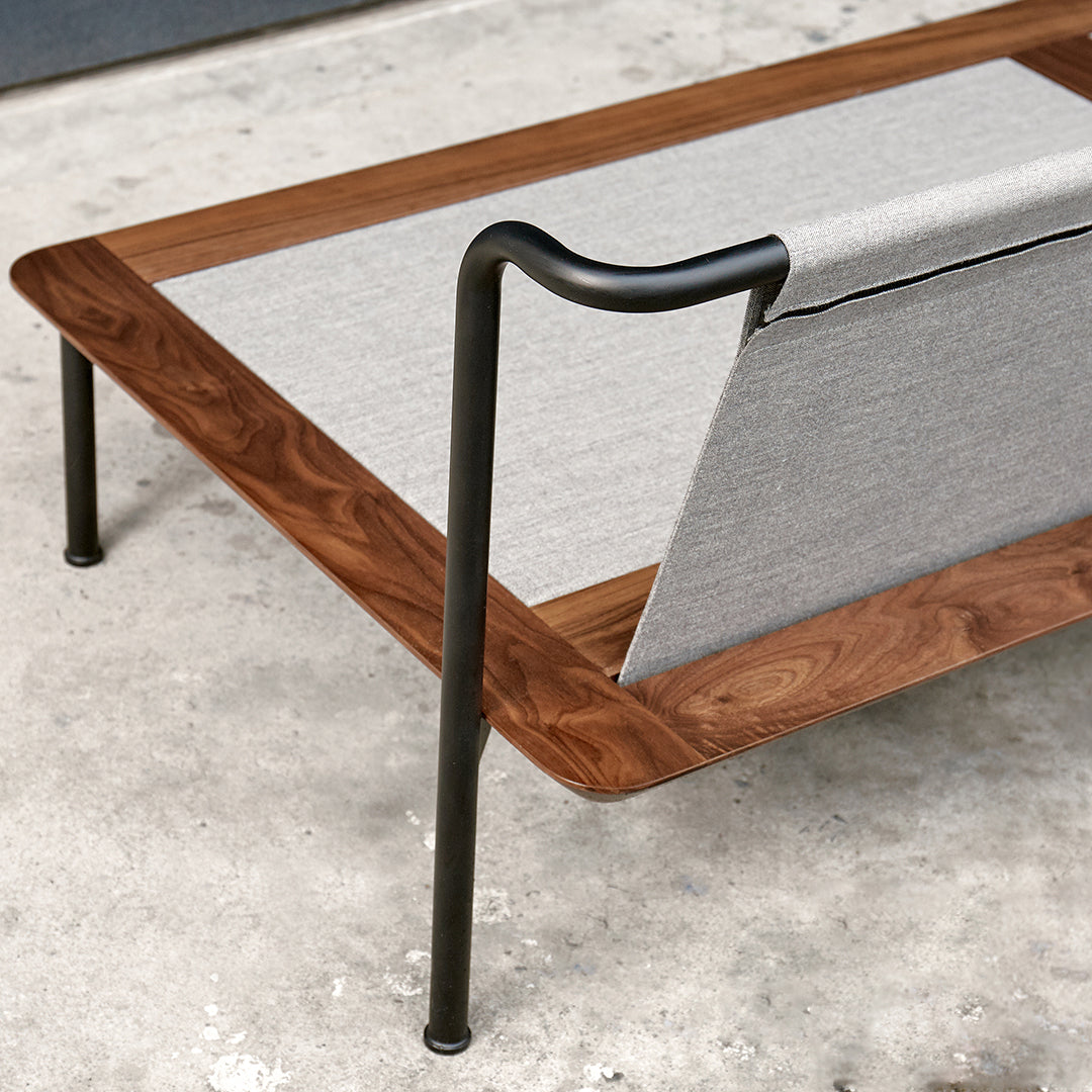 Modern coffee table featuring a sleek walnut finish with a gray fabric accent and black metal legs.
