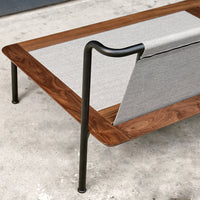 Modern coffee table featuring a sleek walnut finish with a gray fabric accent and black metal legs.