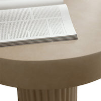 Beige circular table with smooth surface and fluted base, showcasing minimalist design and neutral tones.