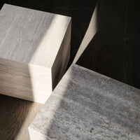 Light beige and gray stone blocks with natural textures, casting soft shadows on a dark wooden surface.
