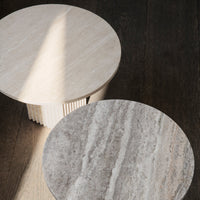 "Round tables featuring light stone and gray marble patterns with textured finishes, set on a dark wooden floor."