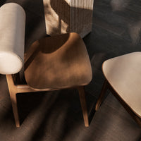Natural wood chairs with soft beige upholstery and curved patterns, set on a dark textured floor.