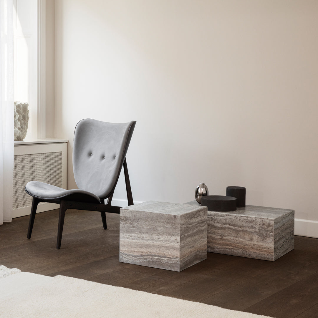 Gray upholstered chair with sleek lines, paired with elegant striped stone cubes in light gray and beige hues.