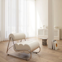 Modern white lounge chair with a unique scalloped design and sleek chrome frame, set in a bright, airy room.