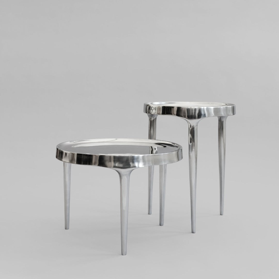 "Modern silver side tables with a sleek, reflective surface and minimalist design on a neutral gray background."