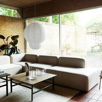 Elegant beige sofa with soft textures, complemented by a minimalist white pendant light and earthy green plants.