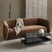 Brown curved sofa with soft fabric, paired with a sleek black marble coffee table and neutral-colored decor.