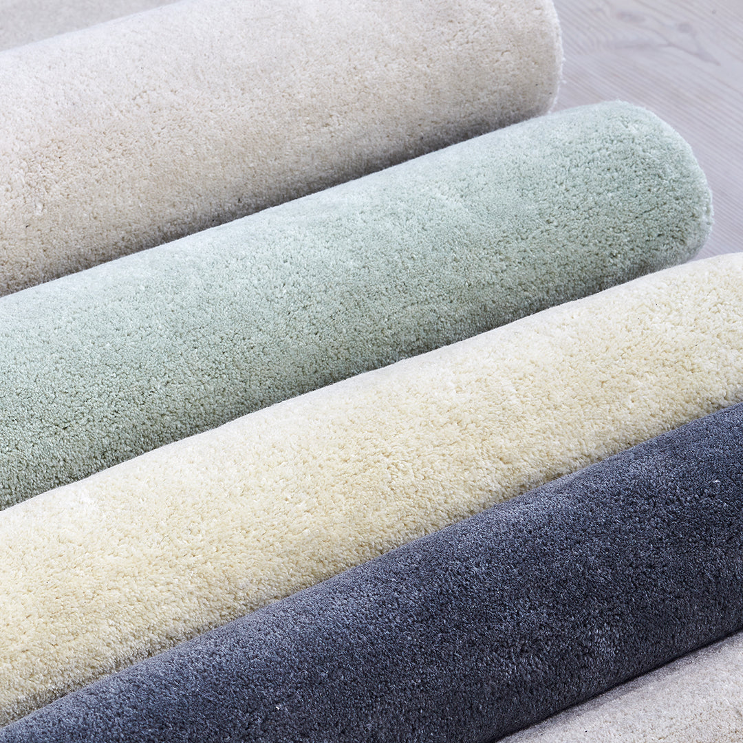 Soft textured fabric rolls in pastel green, cream, light gray, and dark gray shades. Perfect for home decor projects.