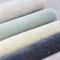 Soft textured fabric rolls in pastel green, cream, light gray, and dark gray shades. Perfect for home decor projects.