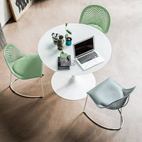 Modern white round table with mint green and light blue patterned chairs, set against a neutral floor.