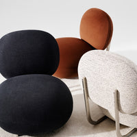 Modern accent chairs in black, rust, and textured cream upholstery with sleek metallic legs.