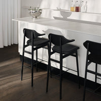 Black bar stools with sleek, minimalist design set against a light, bright countertop and soft shadows.