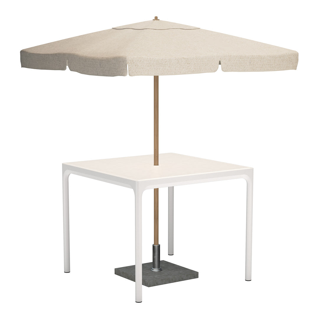 Beige umbrella with a scalloped edge atop a sleek white table with a gray base. Ideal for outdoor elegance.