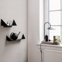 Black minimalist shelves with geometric patterns against a neutral wall, featuring sleek black and silver decor.