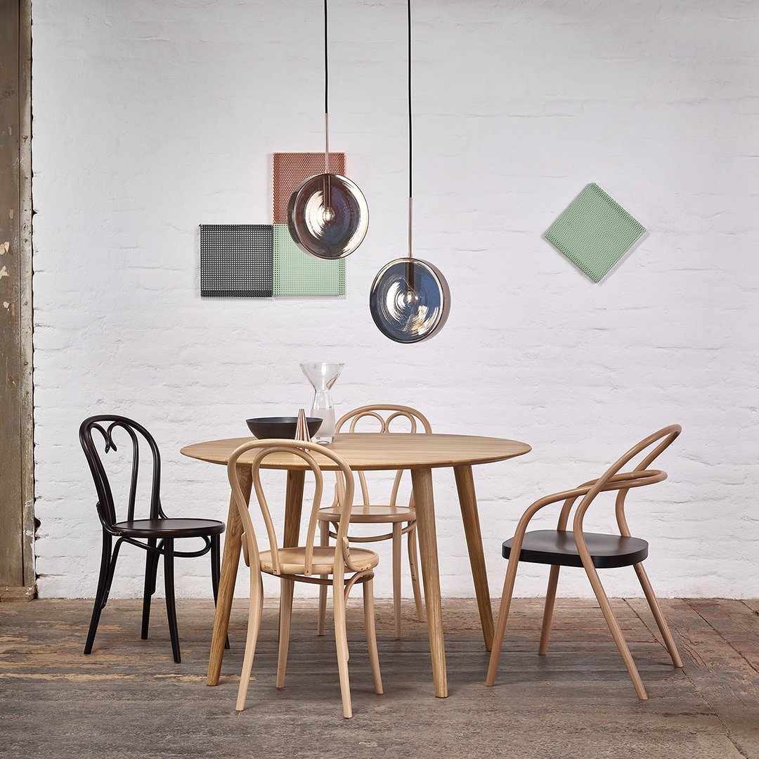 "Modern dining set featuring natural wood tones, black and light chairs, with colorful geometric wall art."