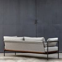 Gray fabric sofa with a sleek black metal frame and warm wooden accents, modern minimalist design.