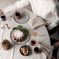 "Neutral table setting with earthy tones, textured napkins, and decorative patterns, featuring a circular cake centerpiece."