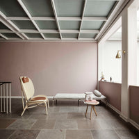 Modern interior featuring muted pink walls, blue-green ceiling, and natural stone flooring. Stylish furniture accents.