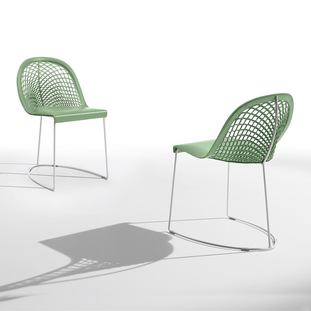 Two mint green chairs with a mesh pattern and sleek metal legs, casting soft shadows on a white background.