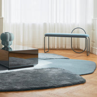 Soft blue and gray area rugs with organic shapes, complemented by a sleek black coffee table and pastel accents.