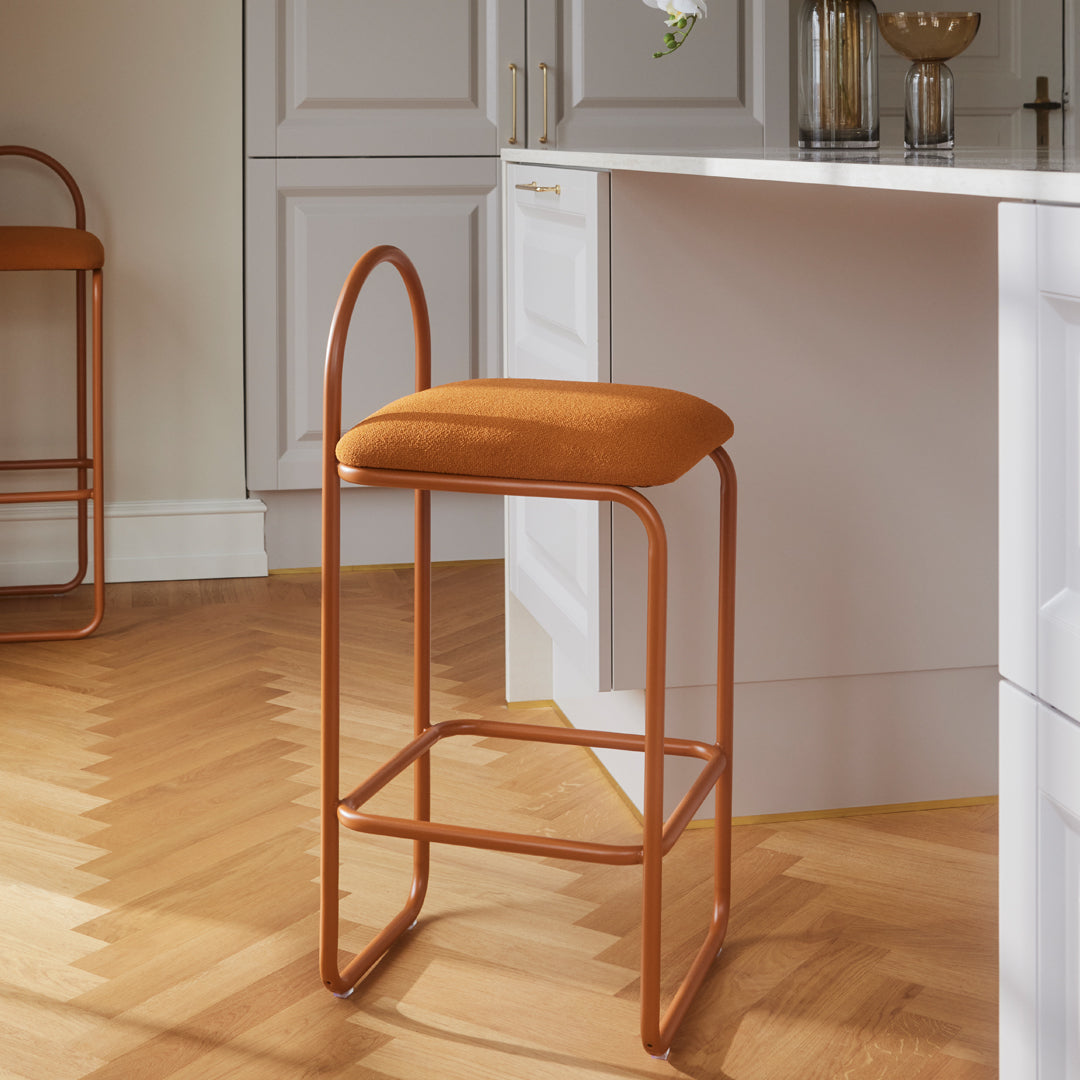 Rust-orange velvet bar stool with sleek copper frame, perfect for modern kitchens or dining areas.