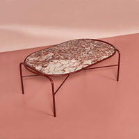 Red and white marble-patterned tabletop coffee table on a pink background. Stylish and modern design accents.