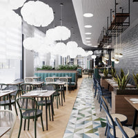 Bright white pendant lights illuminate a modern restaurant with green accents and a geometric patterned floor.